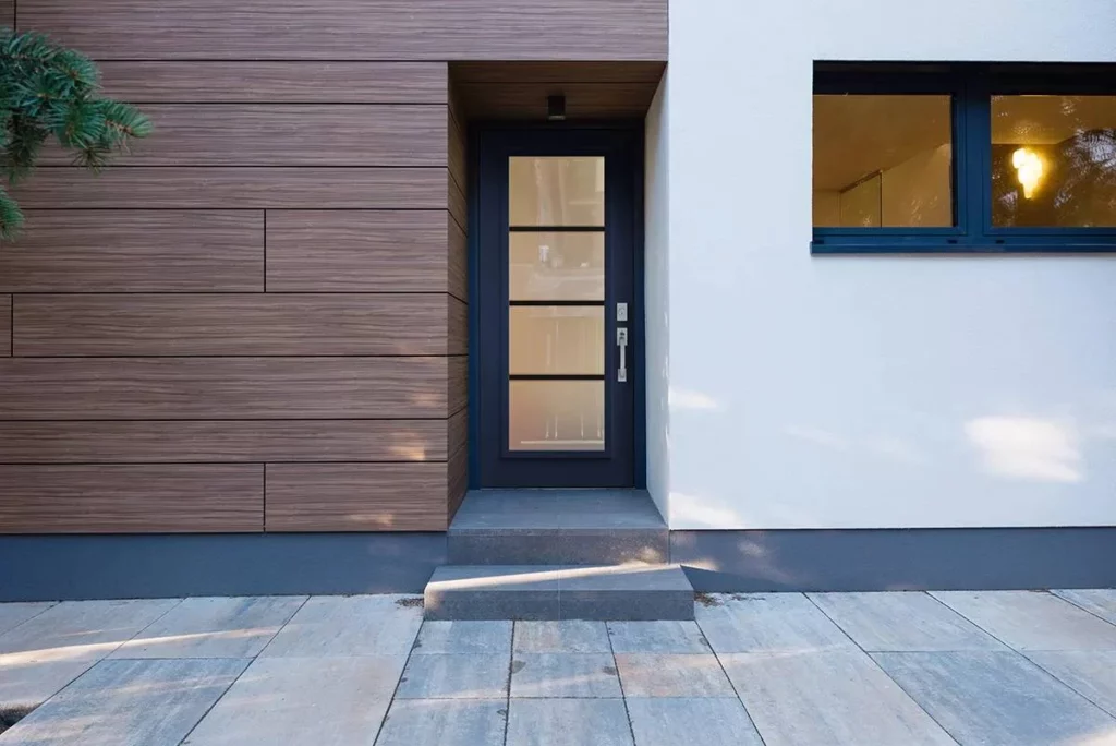 Entrée de maison moderne avec porte noire vitrée et revêtement mural en bois clair.