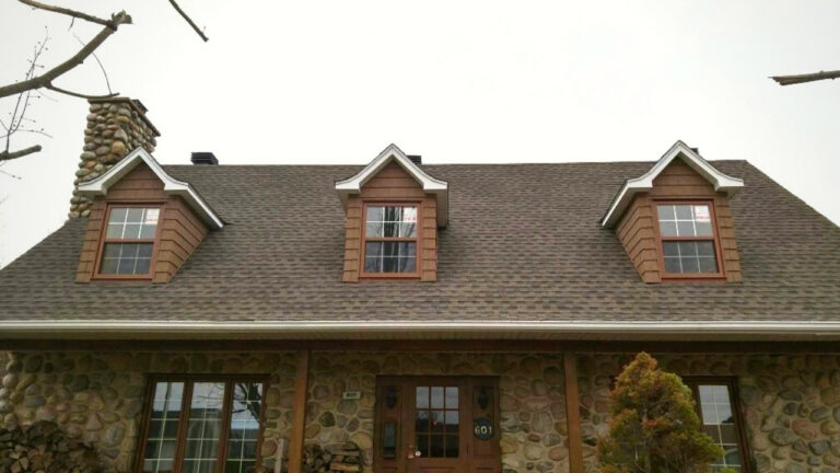 Toit de maison en pierre avec cheminée et lucarnes, style rustique.