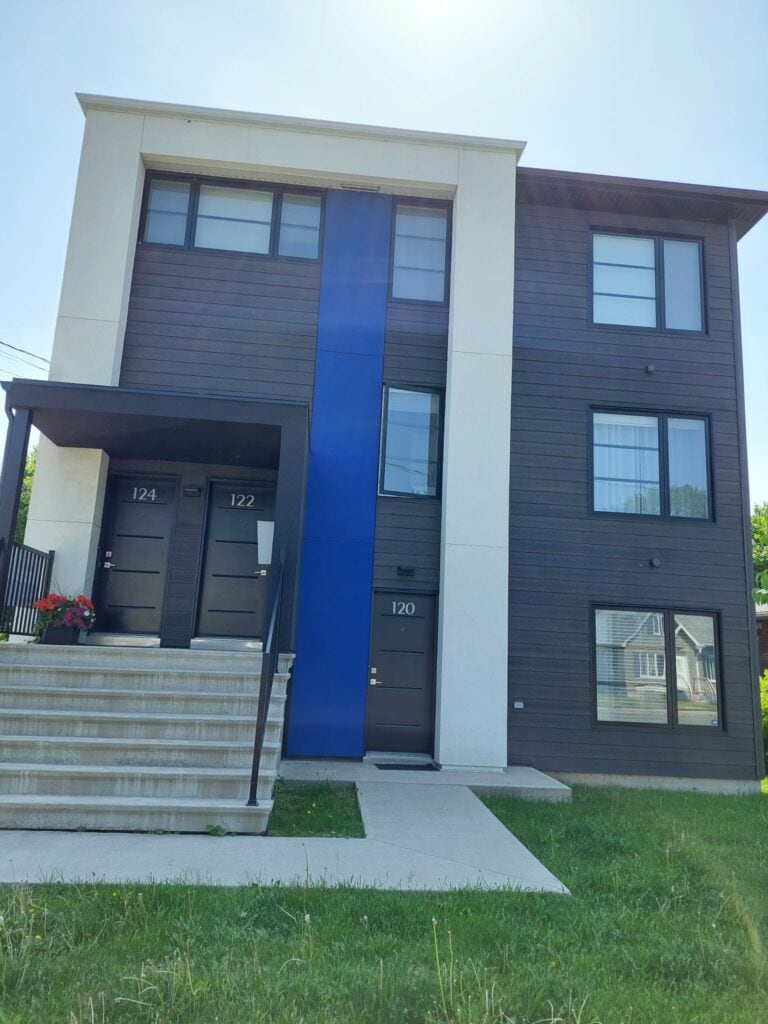 Immeuble moderne à trois étages avec façade bleue et noire et trois portes d'entrée.